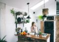A girl in the kitchen leaning on the table and sipping her tea