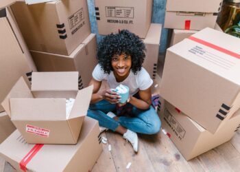 A girl sitting on the floor surrounded by boxes