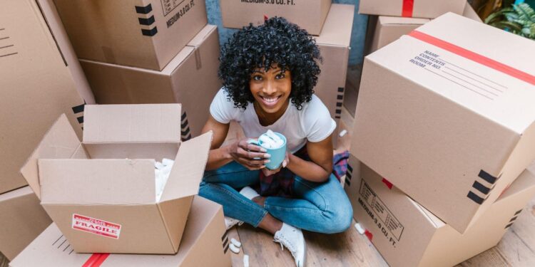 A girl sitting on the floor surrounded by boxes