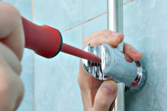 A man adjusting the height of a shower handle