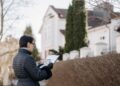 A person checking documents in front of a house