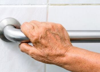 A senior man holding the shower standing handle for support