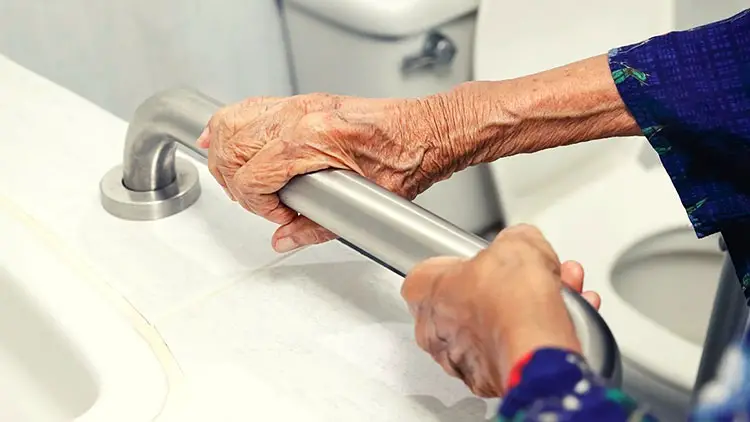 An elderly holding onto a grab bar for support