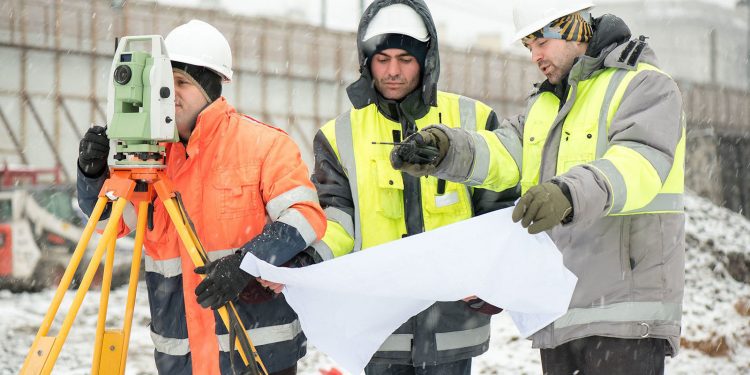 Civil Engineers at construction site are inspecting ongoing production according to design drawings.