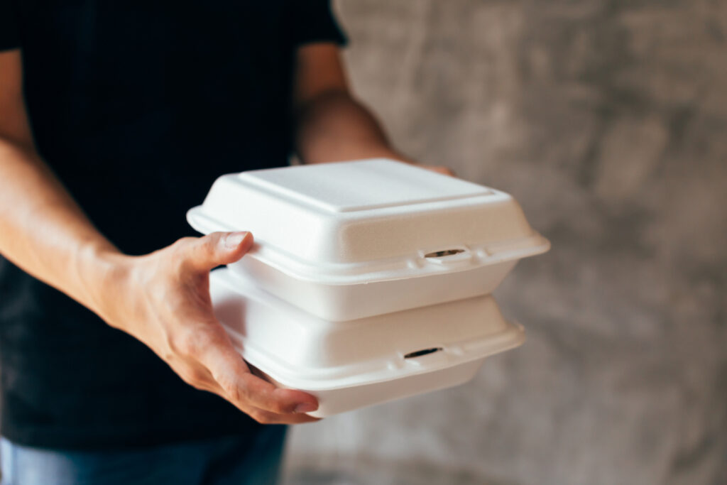 Close-up of delivery man handing a slack of foam lunch box