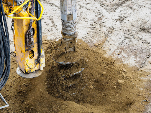 A close up shot of an auger attachment digging the ground
