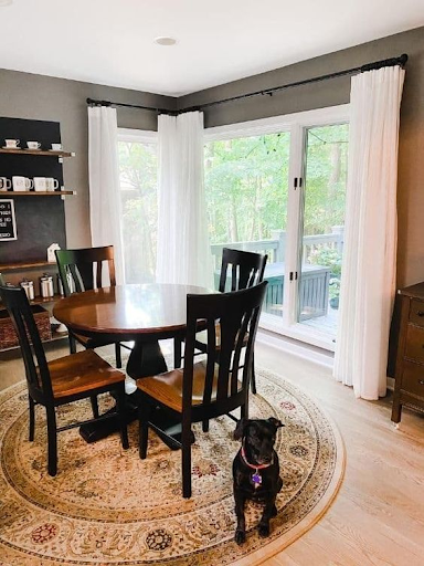 white curtain and dining table with chairs and a dog